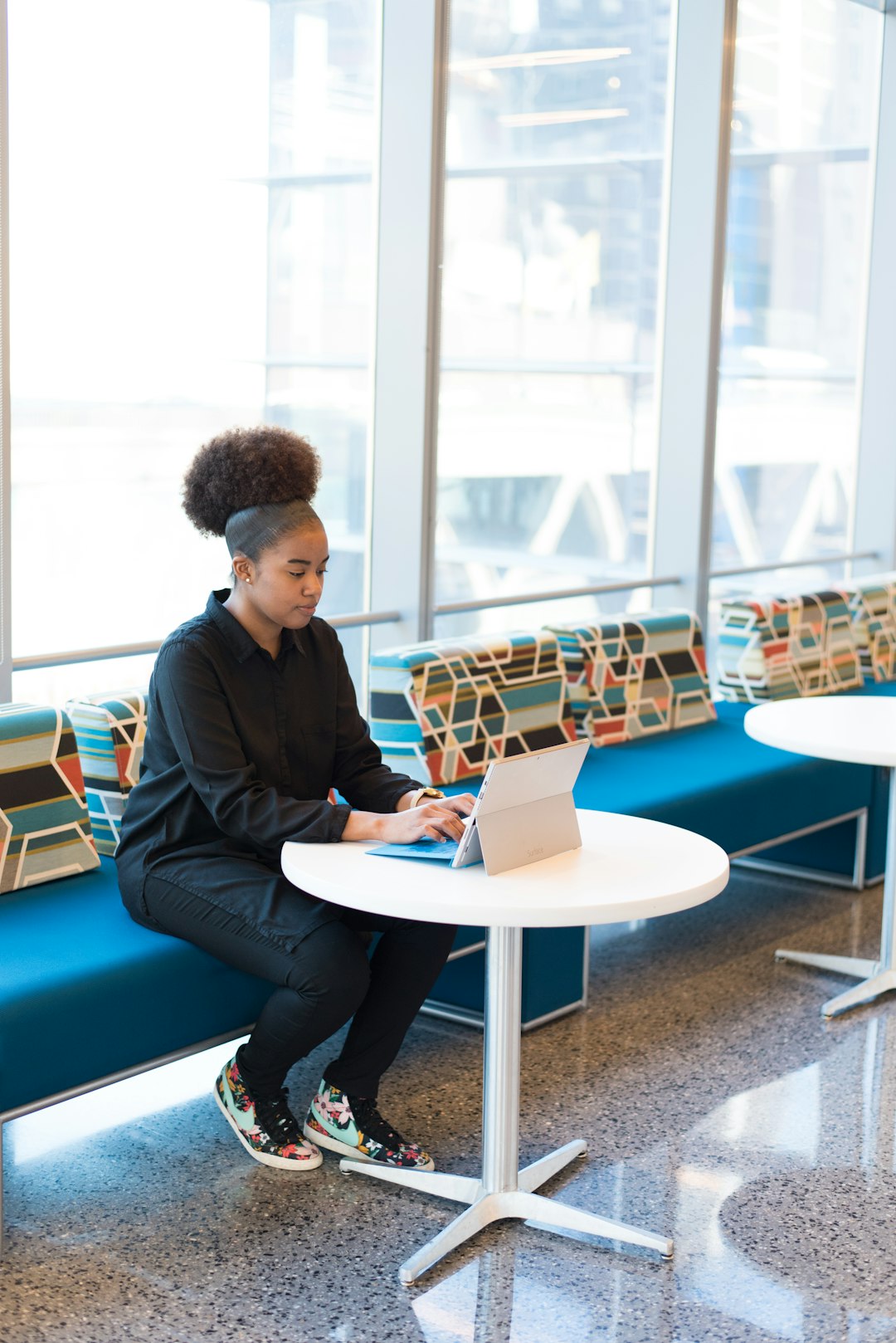 woman-sits-on-sofa-while-using-laptop-computer-fbdmhgmdcso